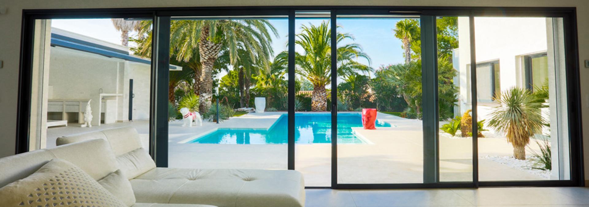 Salon équipe d’une porte fenêtre en alu avec vue sur piscine